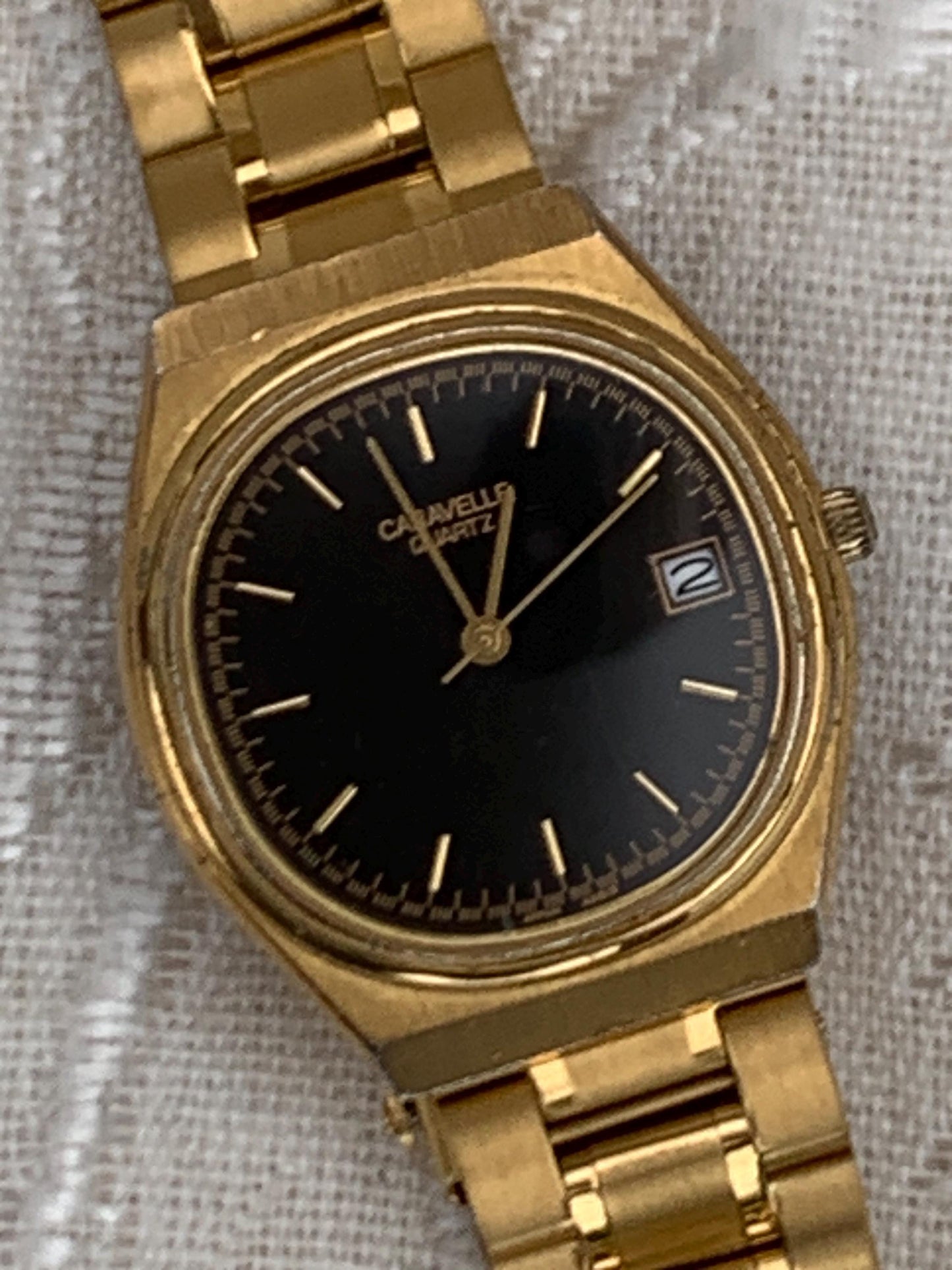 Worn 1992 Caravelle Cushion Quartz Watch by Bolova Gold Tone Finish, Black Dial with Date, New battery. New Bracelet. Presentable.