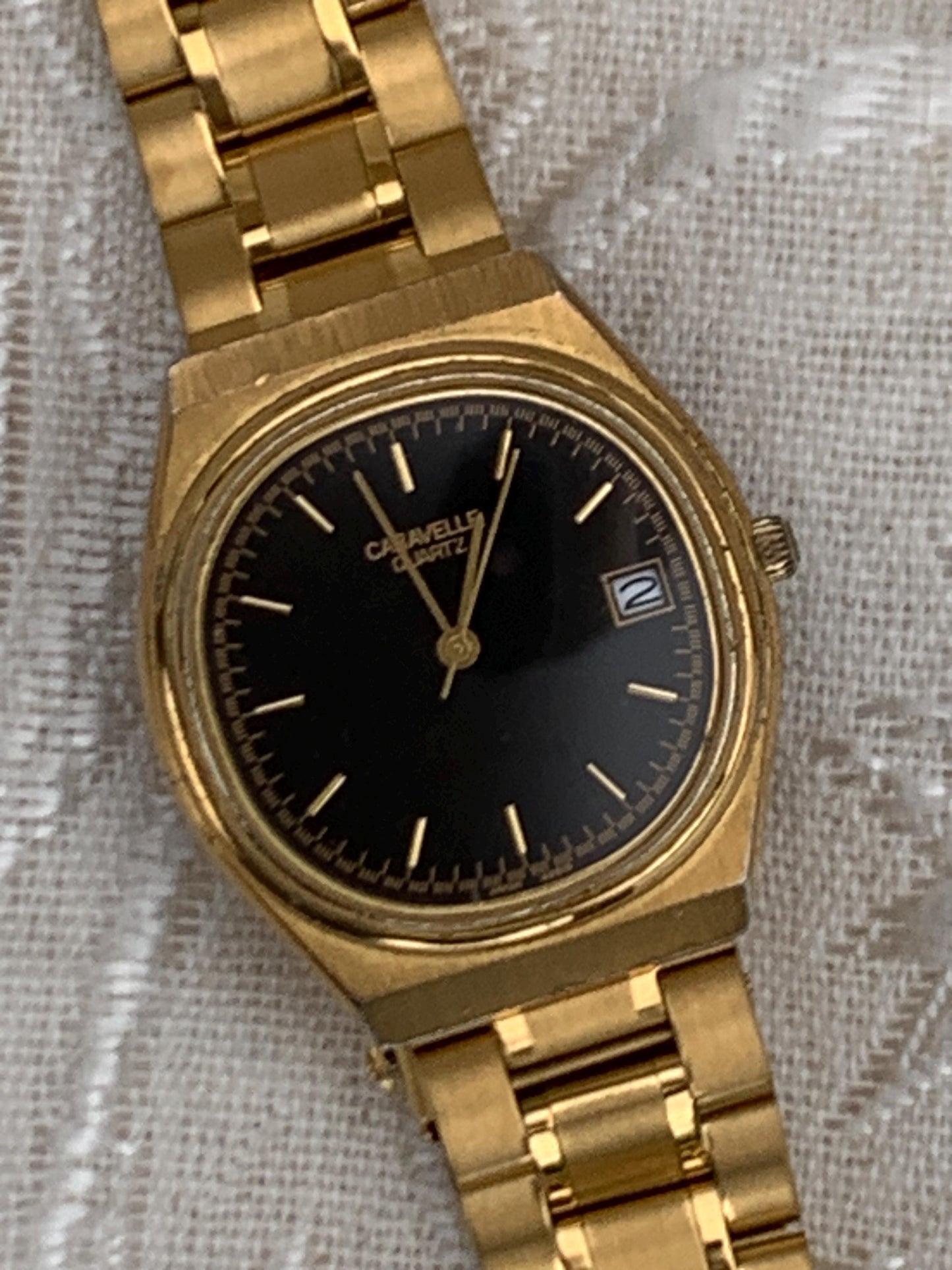 Worn 1992 Caravelle Cushion Quartz Watch by Bolova Gold Tone Finish, Black Dial with Date, New battery. New Bracelet. Presentable.