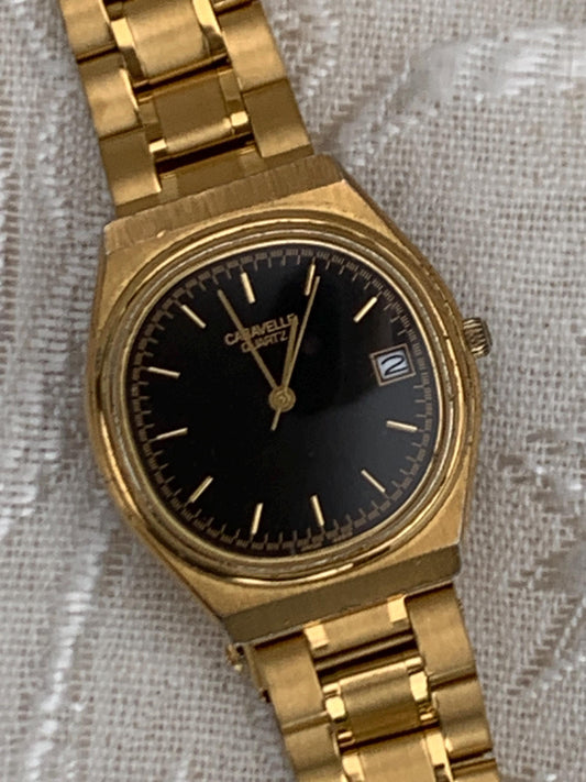 Worn 1992 Caravelle Cushion Quartz Watch by Bolova Gold Tone Finish, Black Dial with Date, New battery. New Bracelet. Presentable.